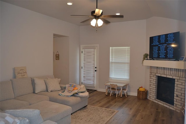 living room featuring hardwood / wood-style flooring, ceiling fan, lofted ceiling, and a fireplace