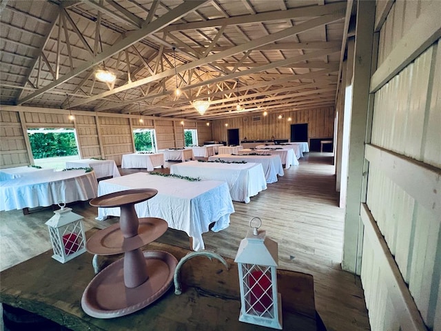 dining area with wood-type flooring, lofted ceiling, and wooden walls