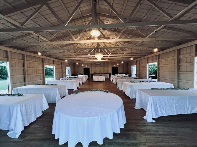 interior space featuring multiple windows, wood walls, lofted ceiling with beams, and dark hardwood / wood-style floors