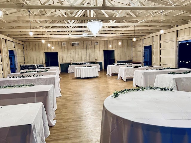 misc room featuring wood-type flooring, wooden walls, and vaulted ceiling