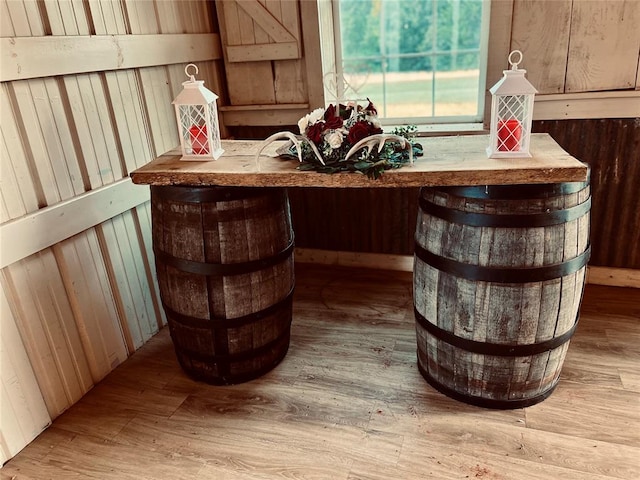 bar with light hardwood / wood-style floors and wooden walls