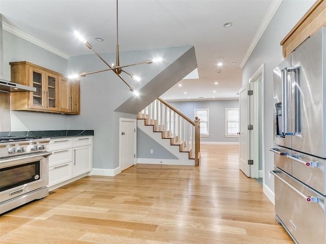 kitchen with white cabinetry, light hardwood / wood-style flooring, high end appliances, and crown molding