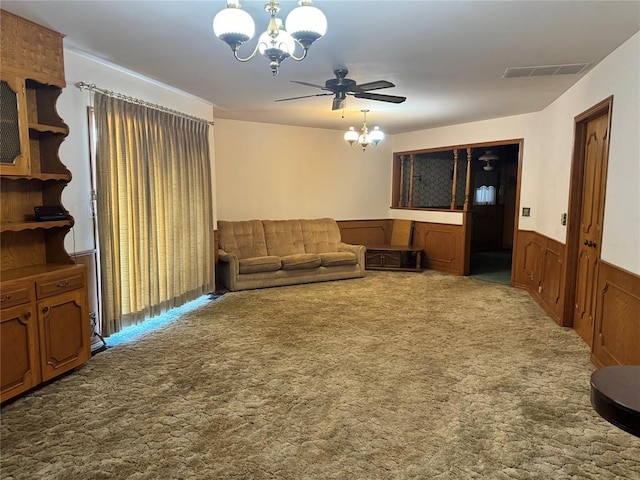 living room featuring ceiling fan with notable chandelier, carpet floors, and wooden walls