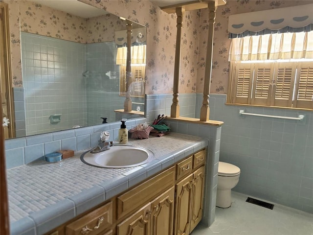 bathroom with vanity, tile walls, and toilet