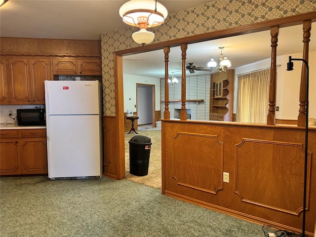 kitchen featuring decorative light fixtures, white fridge, light colored carpet, and ceiling fan with notable chandelier