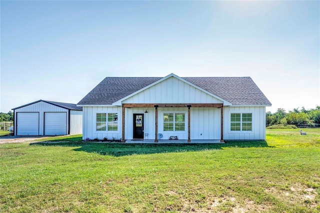 view of front of property featuring a front yard, a garage, an outdoor structure, and covered porch