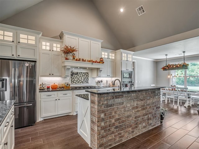 kitchen featuring high vaulted ceiling, dark hardwood / wood-style flooring, hanging light fixtures, and appliances with stainless steel finishes