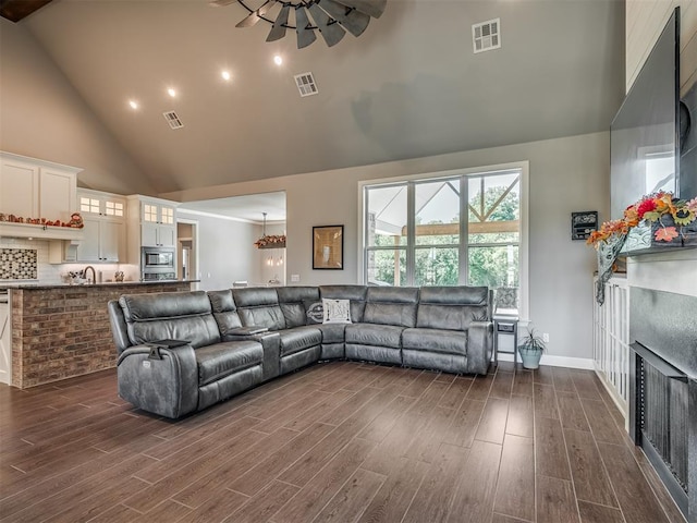 living room featuring ceiling fan, high vaulted ceiling, and dark wood-type flooring