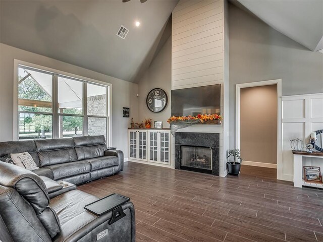 living room featuring dark hardwood / wood-style floors, high vaulted ceiling, and a premium fireplace