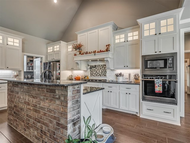 kitchen featuring dark stone countertops, white cabinetry, high vaulted ceiling, and appliances with stainless steel finishes