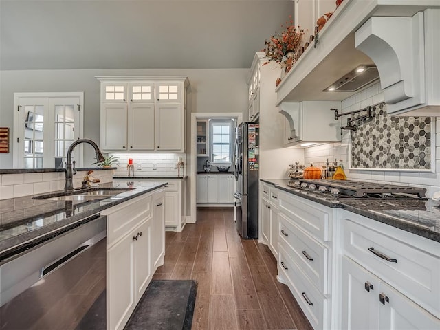 kitchen with dark stone countertops, white cabinetry, sink, and stainless steel appliances