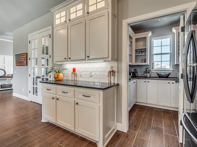 kitchen featuring decorative backsplash, stainless steel refrigerator, dark wood-type flooring, and dark stone countertops