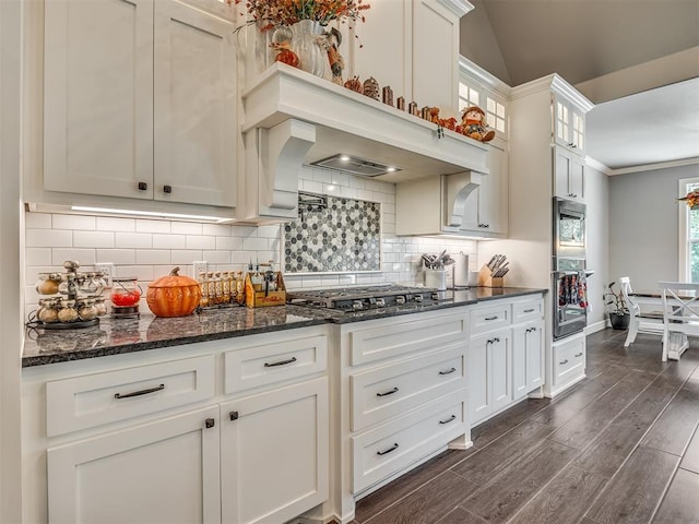 kitchen with decorative backsplash, appliances with stainless steel finishes, dark stone countertops, dark hardwood / wood-style floors, and white cabinetry