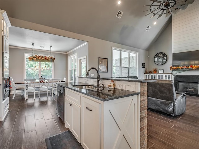 kitchen with white cabinets, decorative light fixtures, a healthy amount of sunlight, and a kitchen island with sink