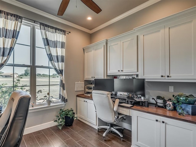 office with ornamental molding, built in desk, ceiling fan, and dark wood-type flooring