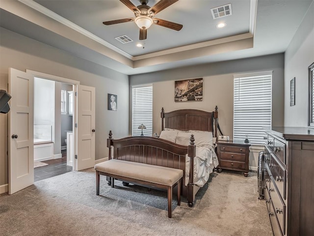 carpeted bedroom with ensuite bathroom, a raised ceiling, ceiling fan, and ornamental molding