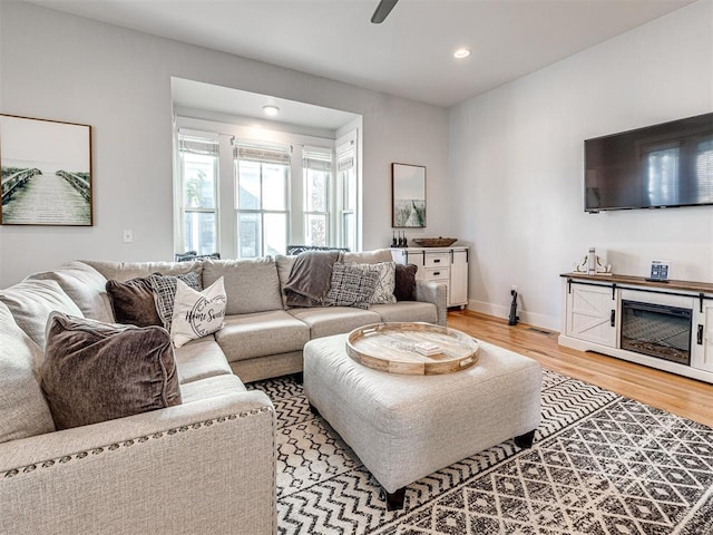 living room with ceiling fan and light hardwood / wood-style flooring