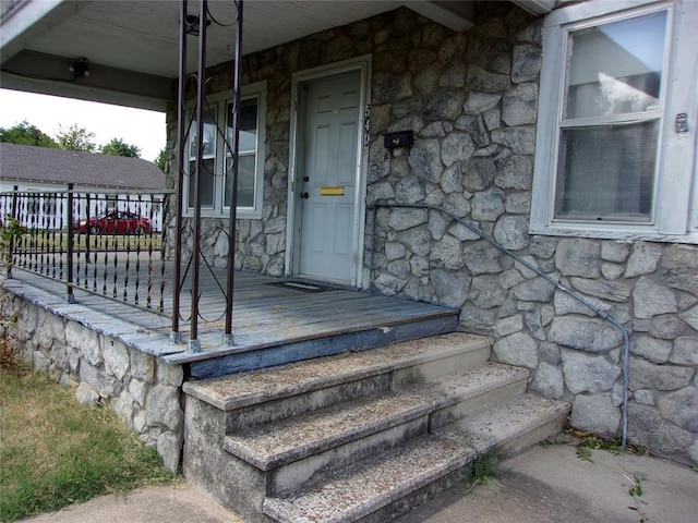 entrance to property featuring covered porch and stone siding