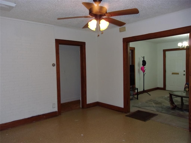 spare room with brick wall, a textured ceiling, and baseboards