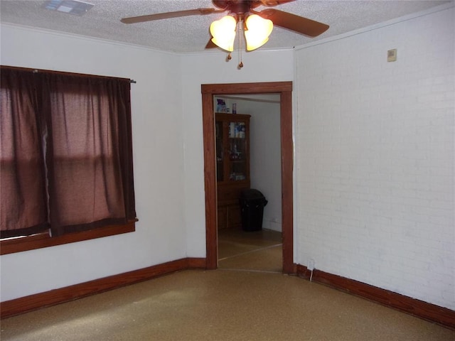 spare room featuring visible vents, a textured ceiling, brick wall, crown molding, and baseboards