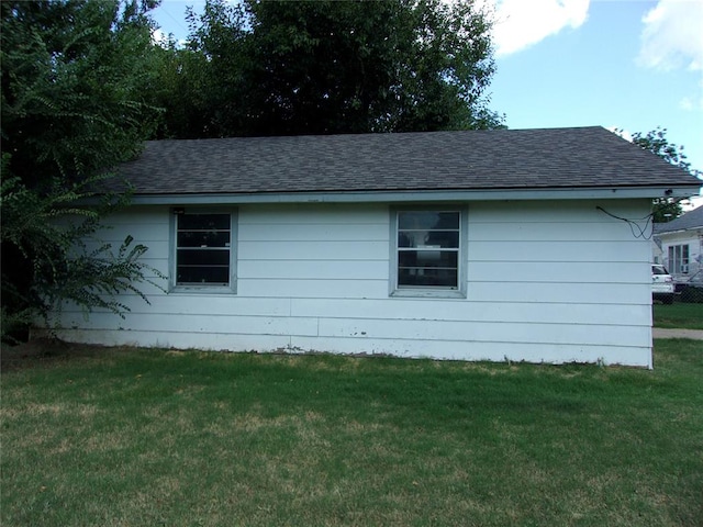 view of property exterior with a lawn and roof with shingles