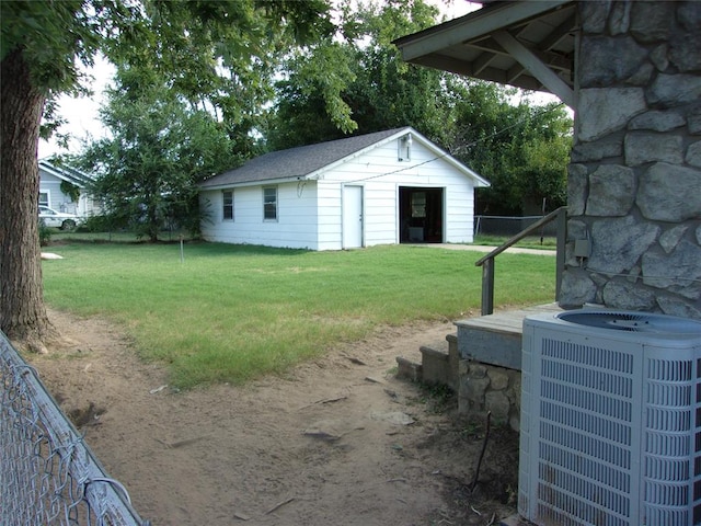 view of yard featuring an outdoor structure, fence, and central AC