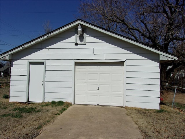 detached garage featuring driveway and fence