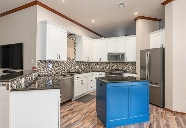 kitchen featuring kitchen peninsula, appliances with stainless steel finishes, white cabinetry, and hardwood / wood-style floors