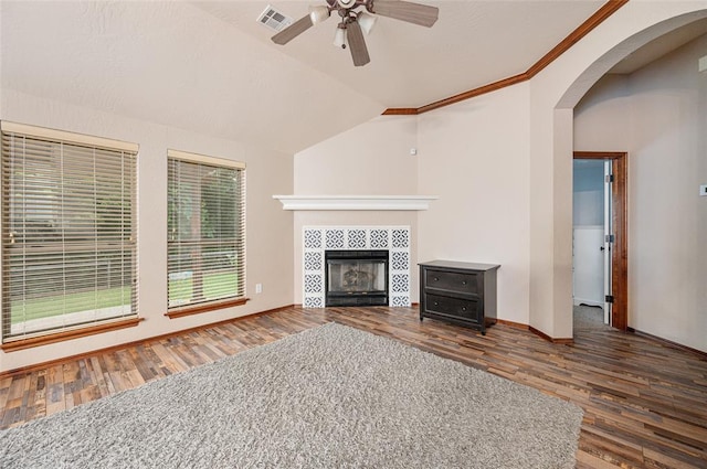 unfurnished living room with vaulted ceiling, ceiling fan, crown molding, a fireplace, and dark hardwood / wood-style floors