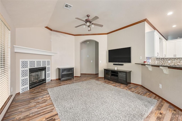 living room with a fireplace, dark hardwood / wood-style flooring, vaulted ceiling, and crown molding