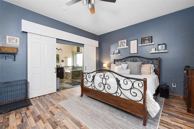 bedroom with hardwood / wood-style flooring, ceiling fan, and ensuite bath