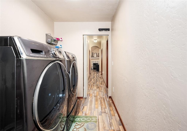 laundry room with wood-type flooring and washing machine and clothes dryer