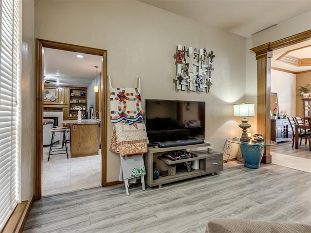 living room featuring light wood-type flooring, crown molding, and a tiled fireplace