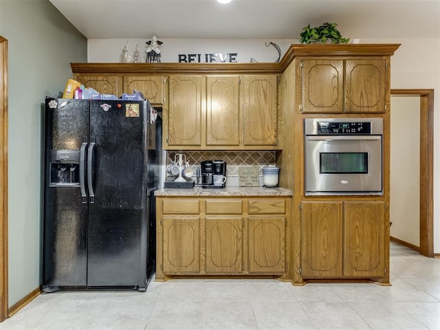 kitchen featuring black fridge with ice dispenser, backsplash, light tile patterned floors, and stainless steel oven