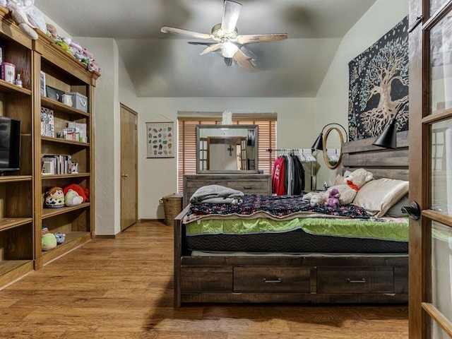 bedroom with ceiling fan, light wood-type flooring, and vaulted ceiling