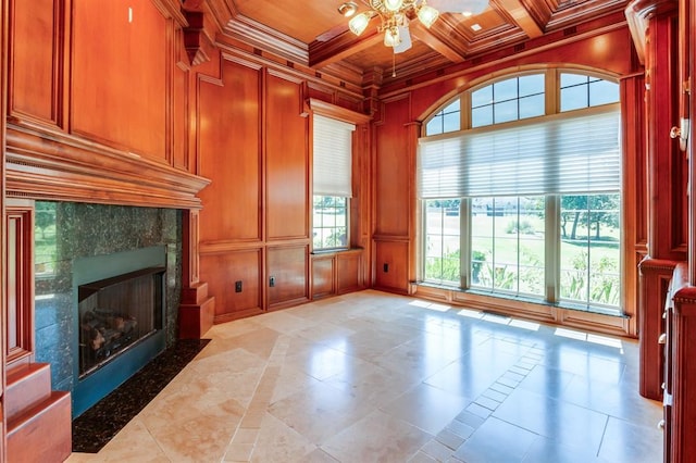 unfurnished living room featuring ceiling fan, a fireplace, beamed ceiling, ornamental molding, and wood ceiling