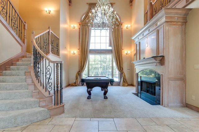 playroom with a towering ceiling, pool table, a chandelier, light carpet, and light tile patterned flooring