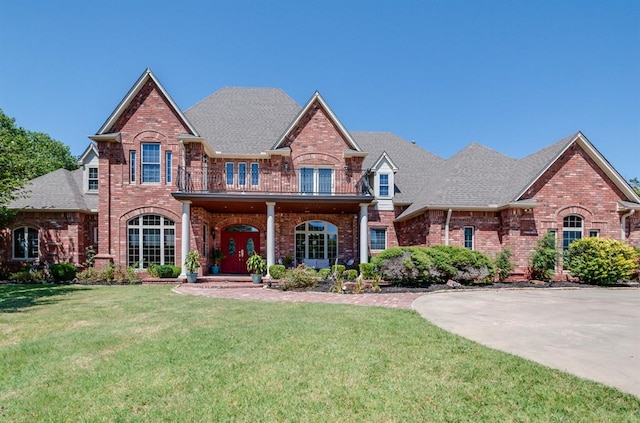 view of front of home with brick siding, a balcony, and a front lawn