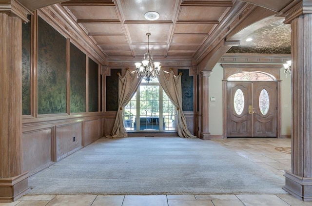 carpeted entryway with wooden ceiling, ornate columns, an inviting chandelier, and ornamental molding