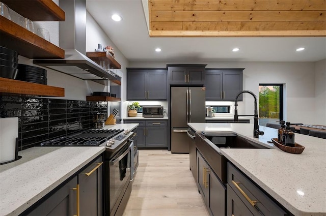 kitchen featuring light hardwood / wood-style flooring, decorative backsplash, light stone countertops, appliances with stainless steel finishes, and extractor fan