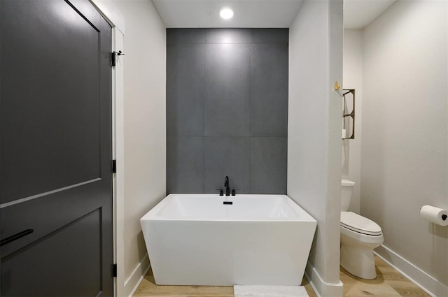 bathroom featuring a bath, wood-type flooring, and toilet