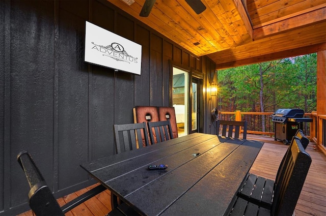 wooden terrace with exterior bar, ceiling fan, and a grill