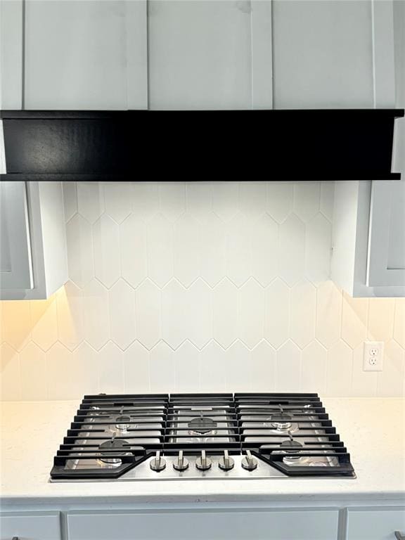 details with backsplash, white cabinets, and stainless steel gas cooktop