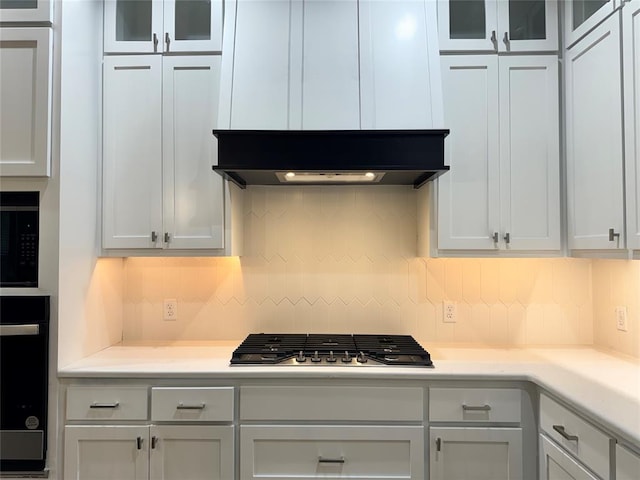 kitchen with range hood, backsplash, black appliances, and white cabinetry