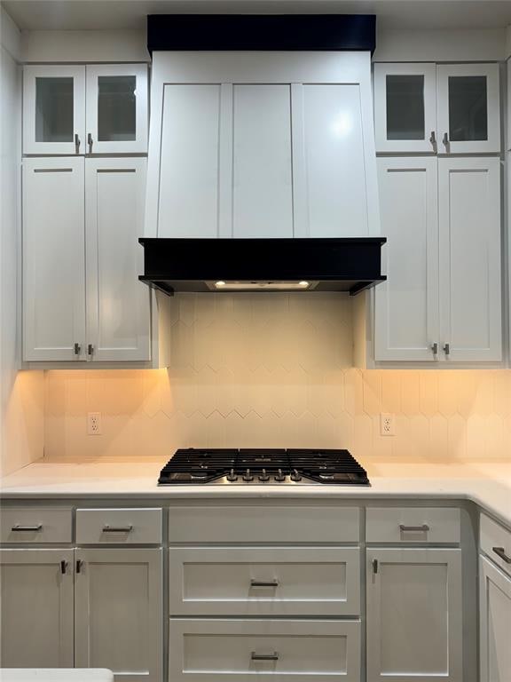 kitchen with stainless steel gas stovetop, backsplash, white cabinetry, and exhaust hood