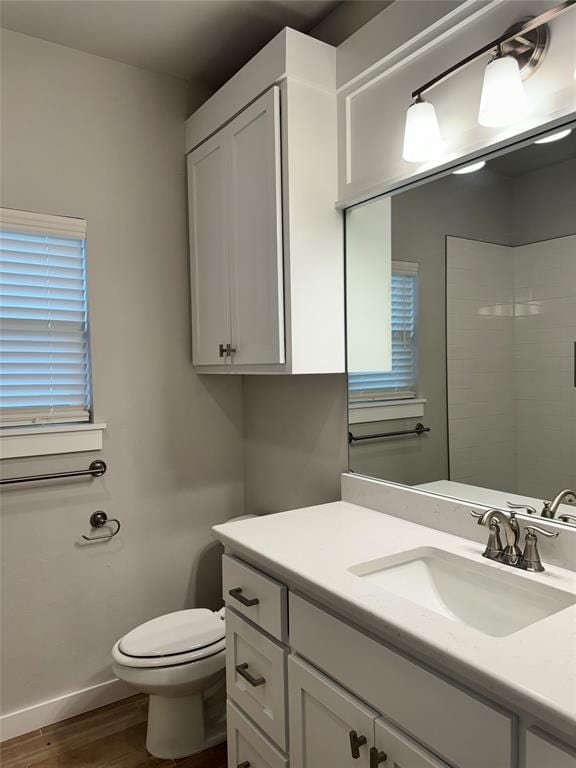 bathroom with hardwood / wood-style floors, a shower, toilet, and vanity