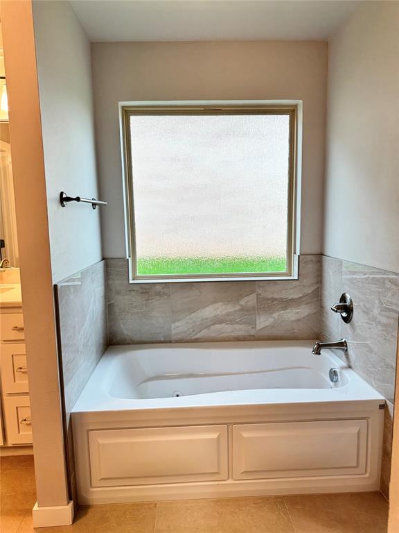 bathroom with tile patterned floors, a tub to relax in, and a healthy amount of sunlight