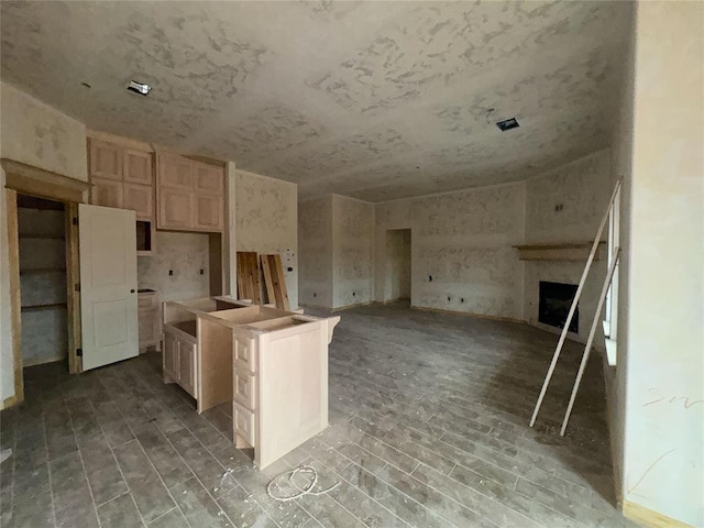 kitchen with light brown cabinets, a fireplace, a kitchen island, and open floor plan