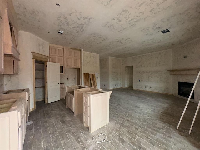 kitchen with a center island, a fireplace, open floor plan, light brown cabinets, and wood finished floors