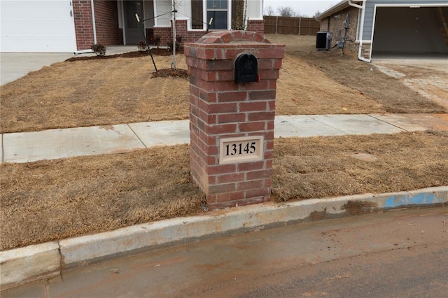 exterior details with brick siding, driveway, and central AC unit